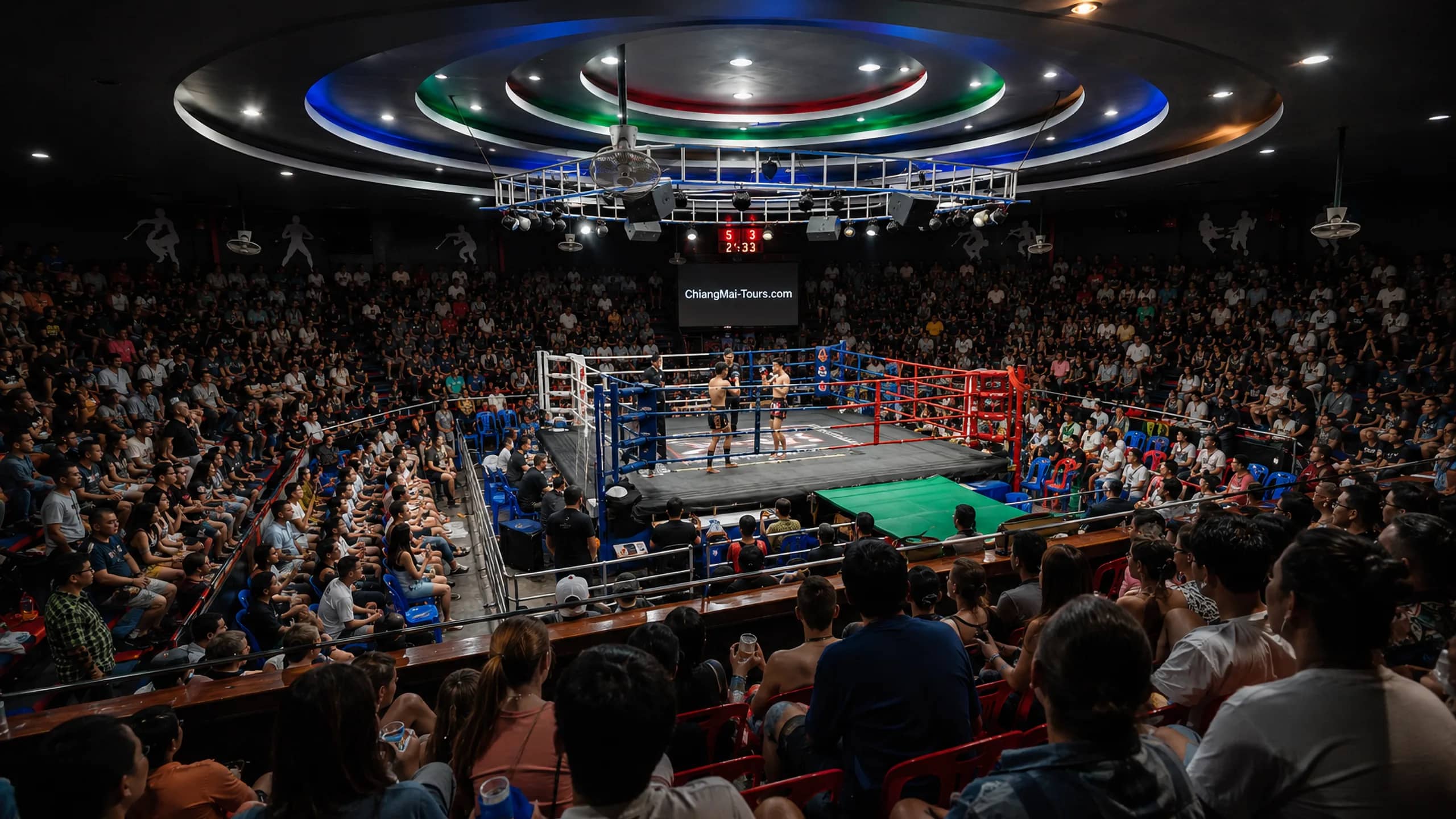 A wide view of the crowded arena and lit ring at Chiang Mai Boxing Stadium