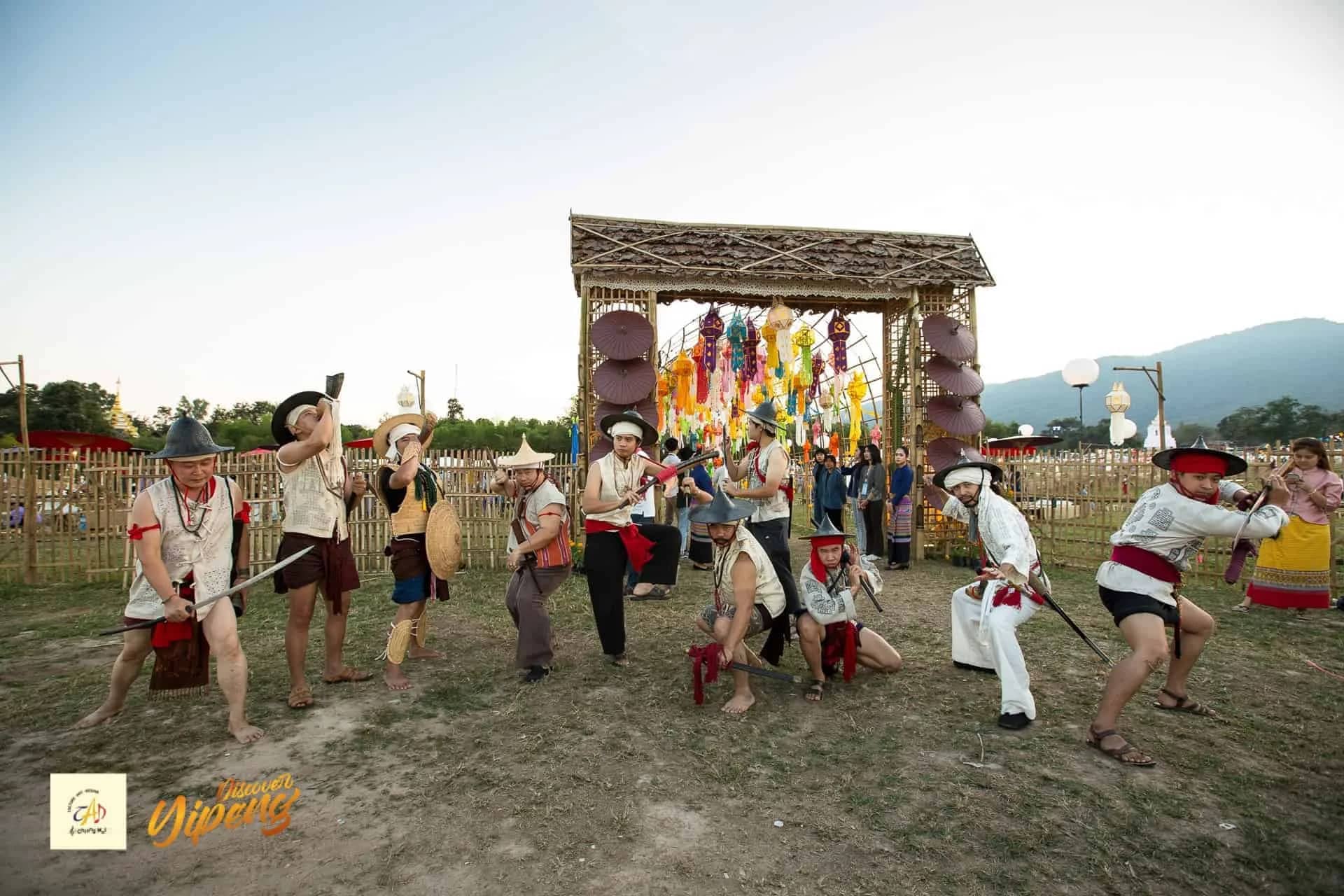 Performers in traditional dress hold swords during a dance in front of a decorated bamboo gate