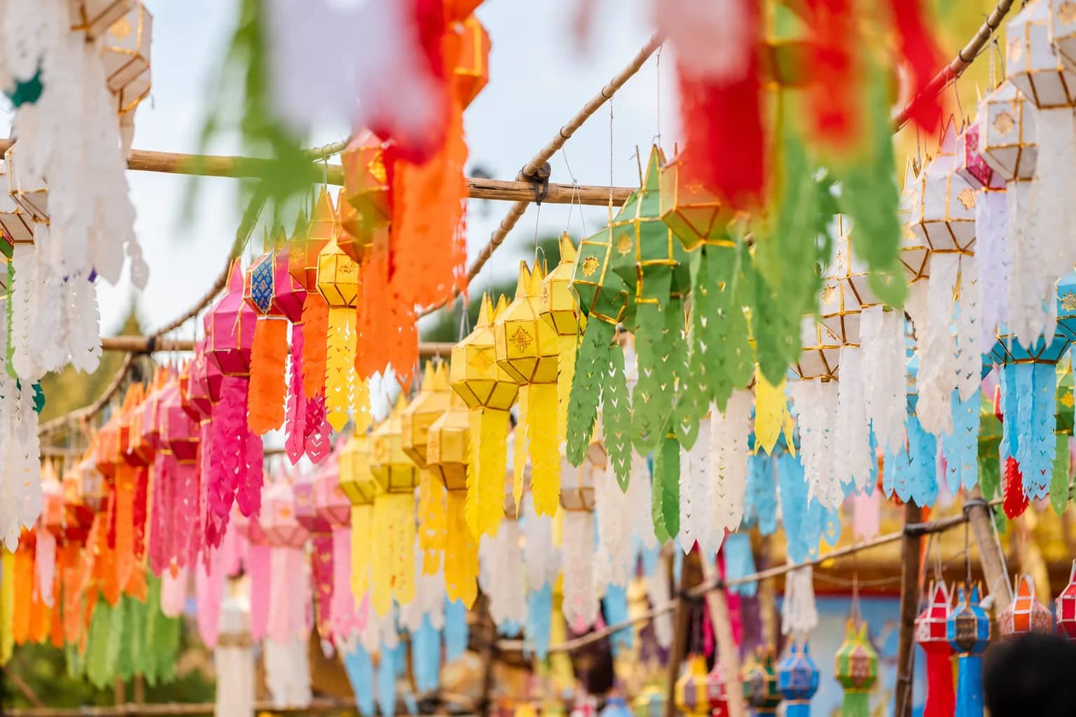 Rows of colourful hanging Lanna paper lanterns and flags decorate a festival ground