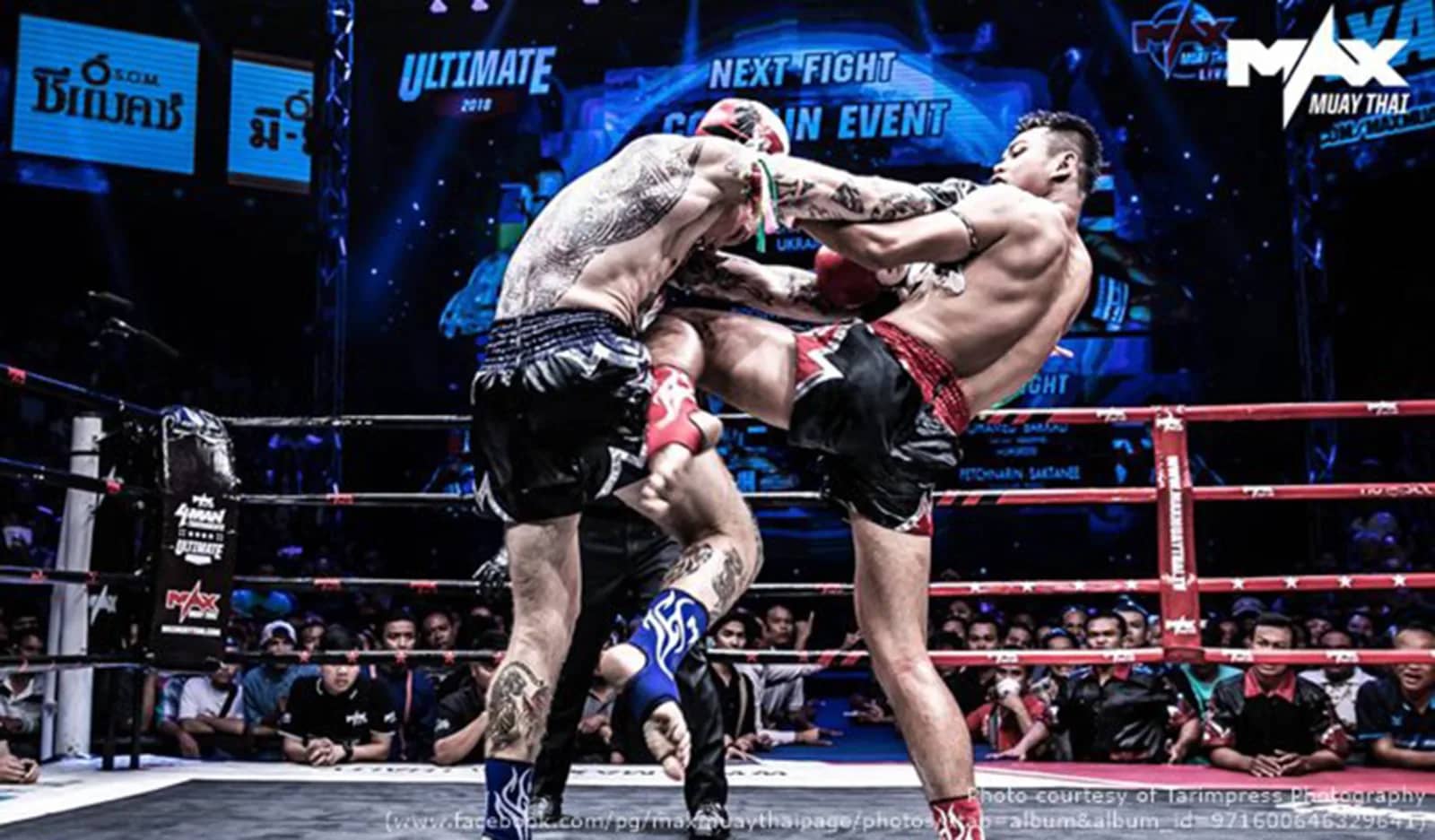 Two tattooed fighters clinch and trade knees inside the ring at Max Muay Thai