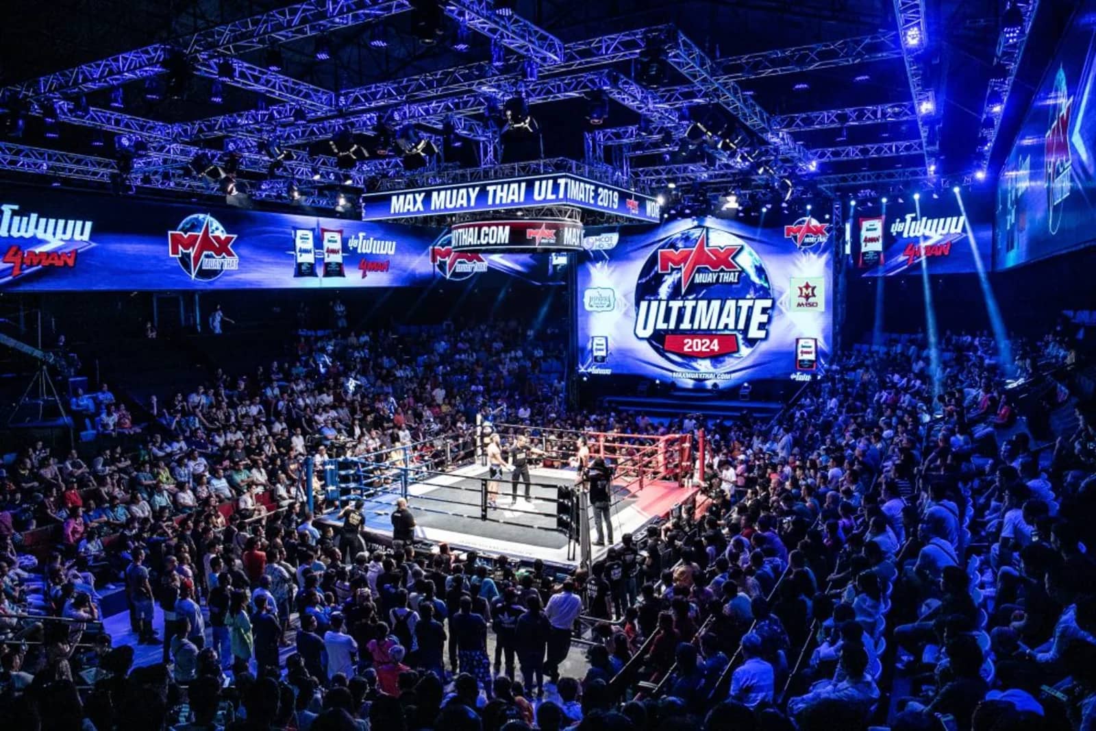 A full arena watches the ring under the Max Muay Thai Ultimate screen and stage lighting