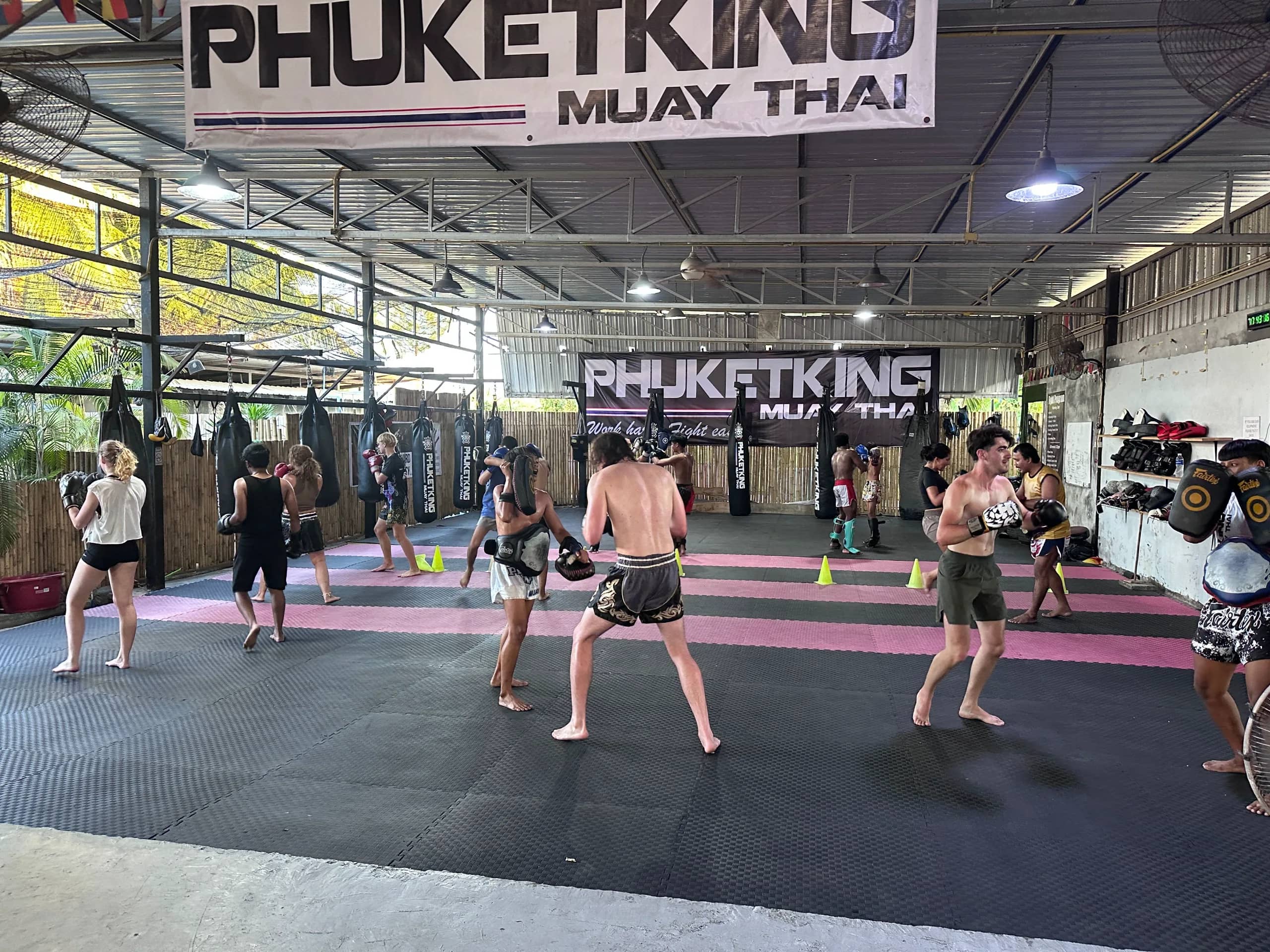 Students practise techniques in pairs across the large covered training floor of Phuket King Muay Thai