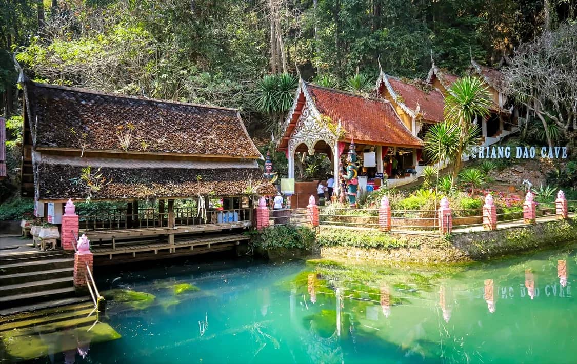 Turquoise water in front of the temple buildings at the entrance to Chiang Dao Cave