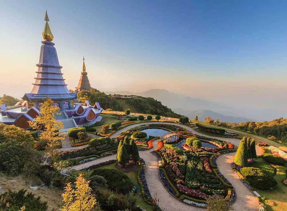 Landscaped gardens wind below the two royal pagodas on Doi Inthanon with mountain views in soft light.
