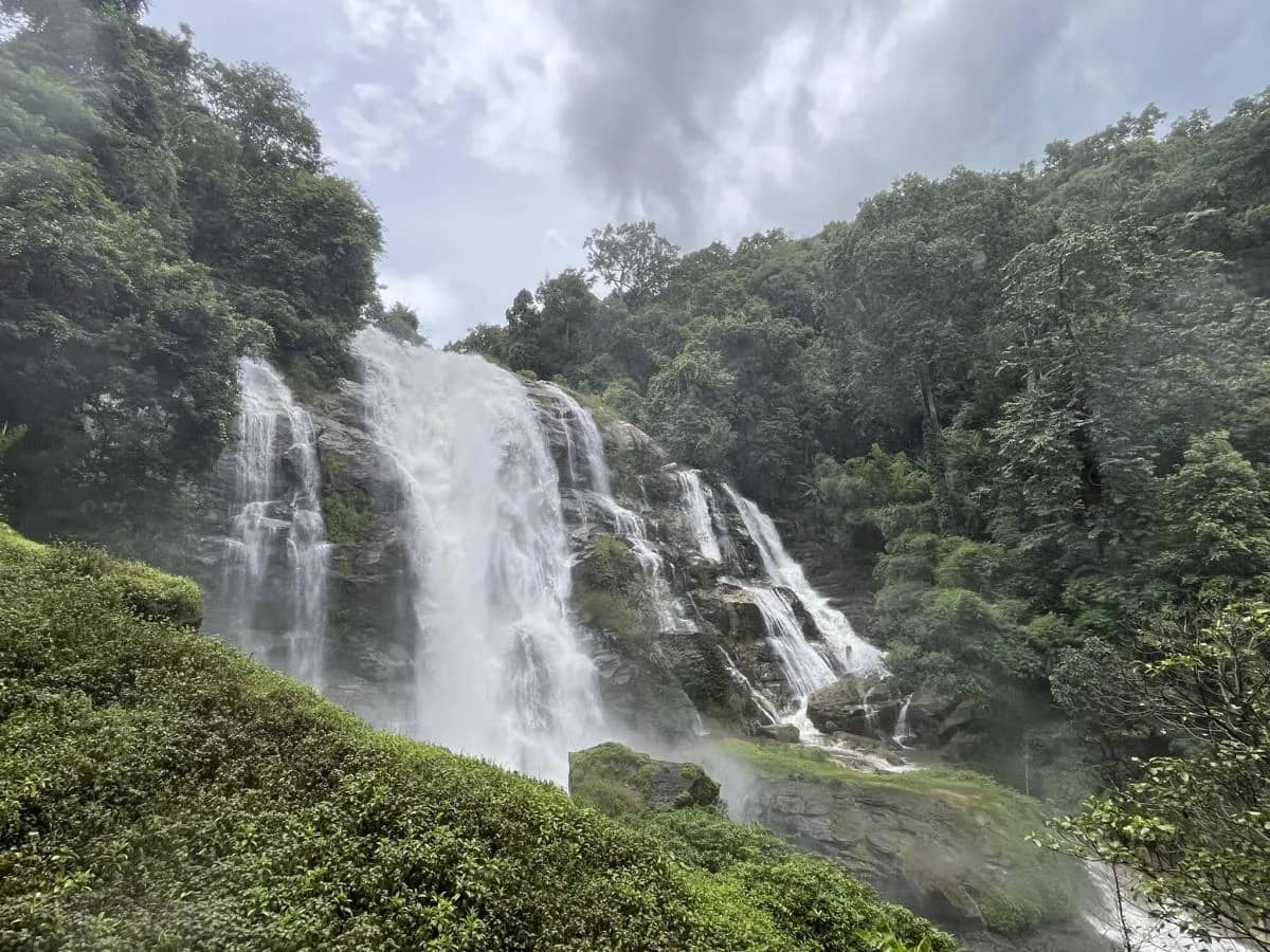 A powerful multi-tiered waterfall pours down a forested cliff in Doi Inthanon National Park