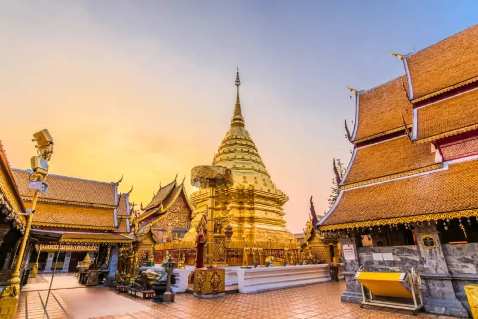 The golden chedi and ornate temple halls of Wat Phra That Doi Suthep glow at sunset.