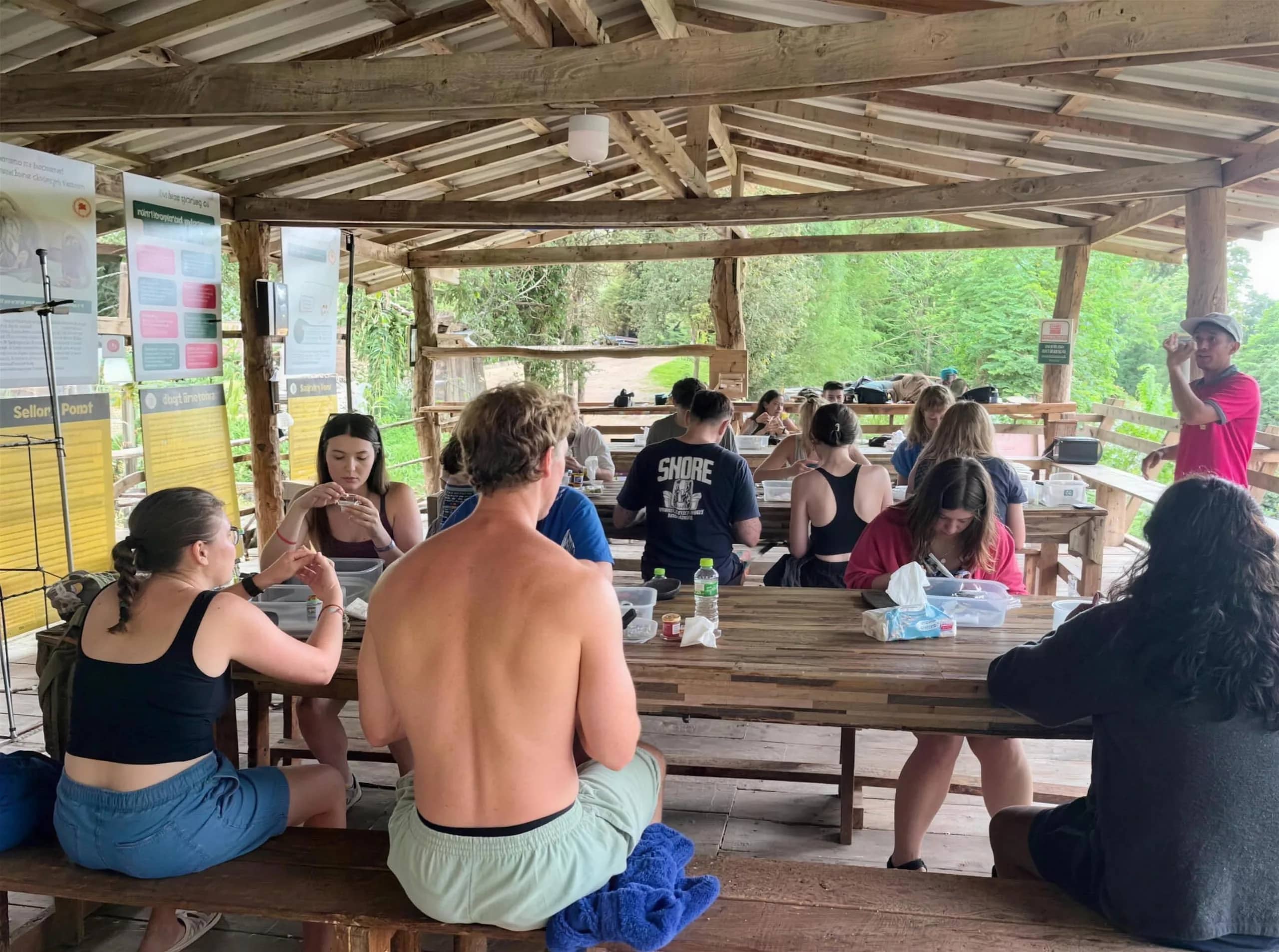 Guests sit at long wooden tables under an open-air pavilion during an elephant camp visit near Chiang Mai