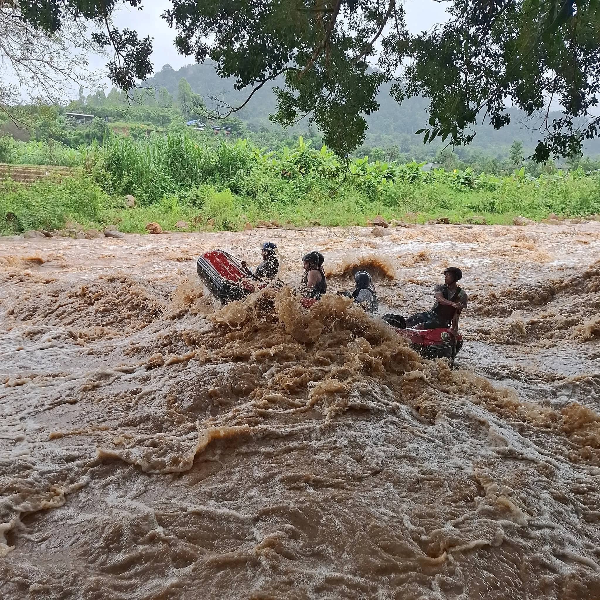 A rafting team in helmets plunges into a big brown wave on a fast flowing river
