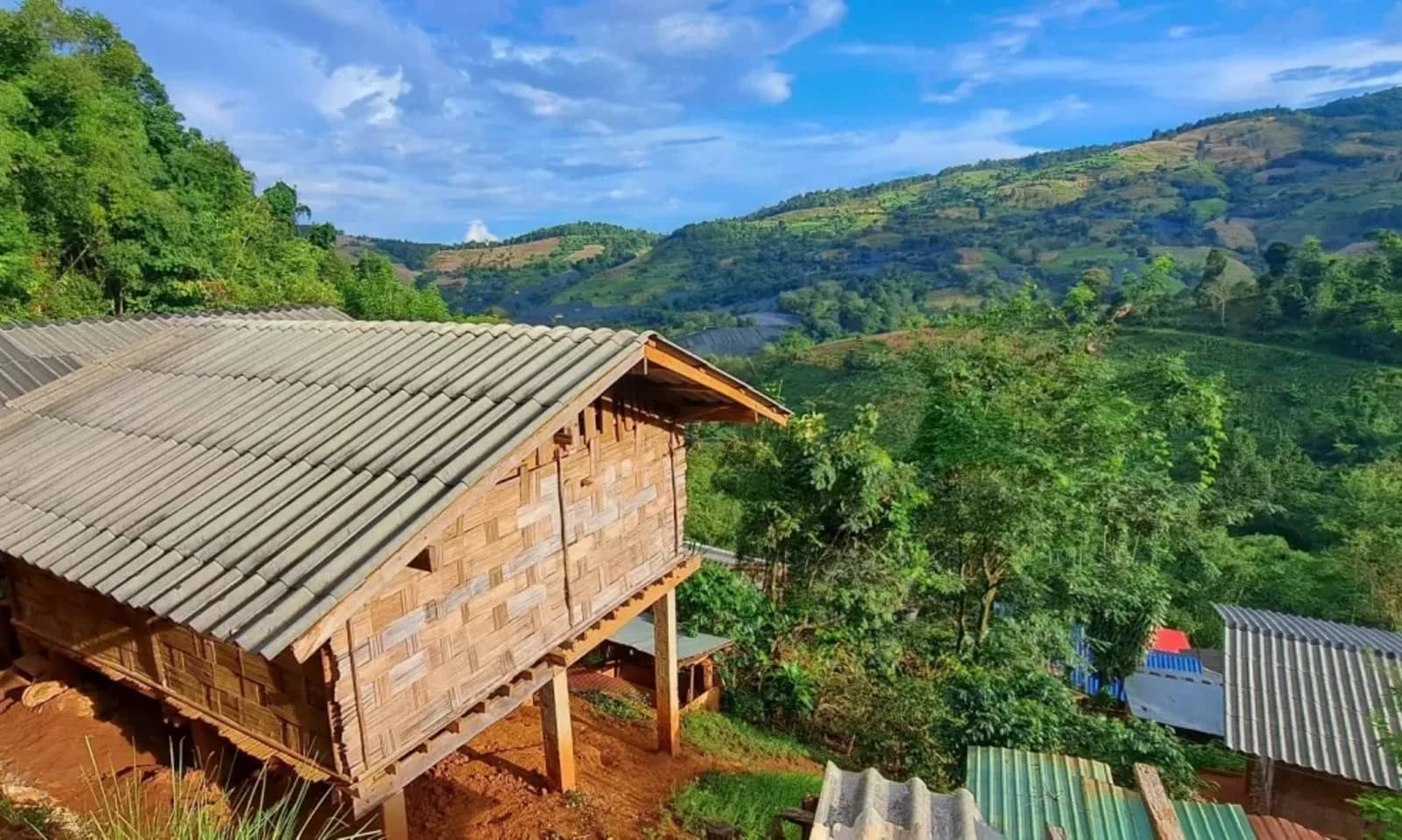 A wooden hut on stilts overlooks green hills and terraced slopes in the highlands