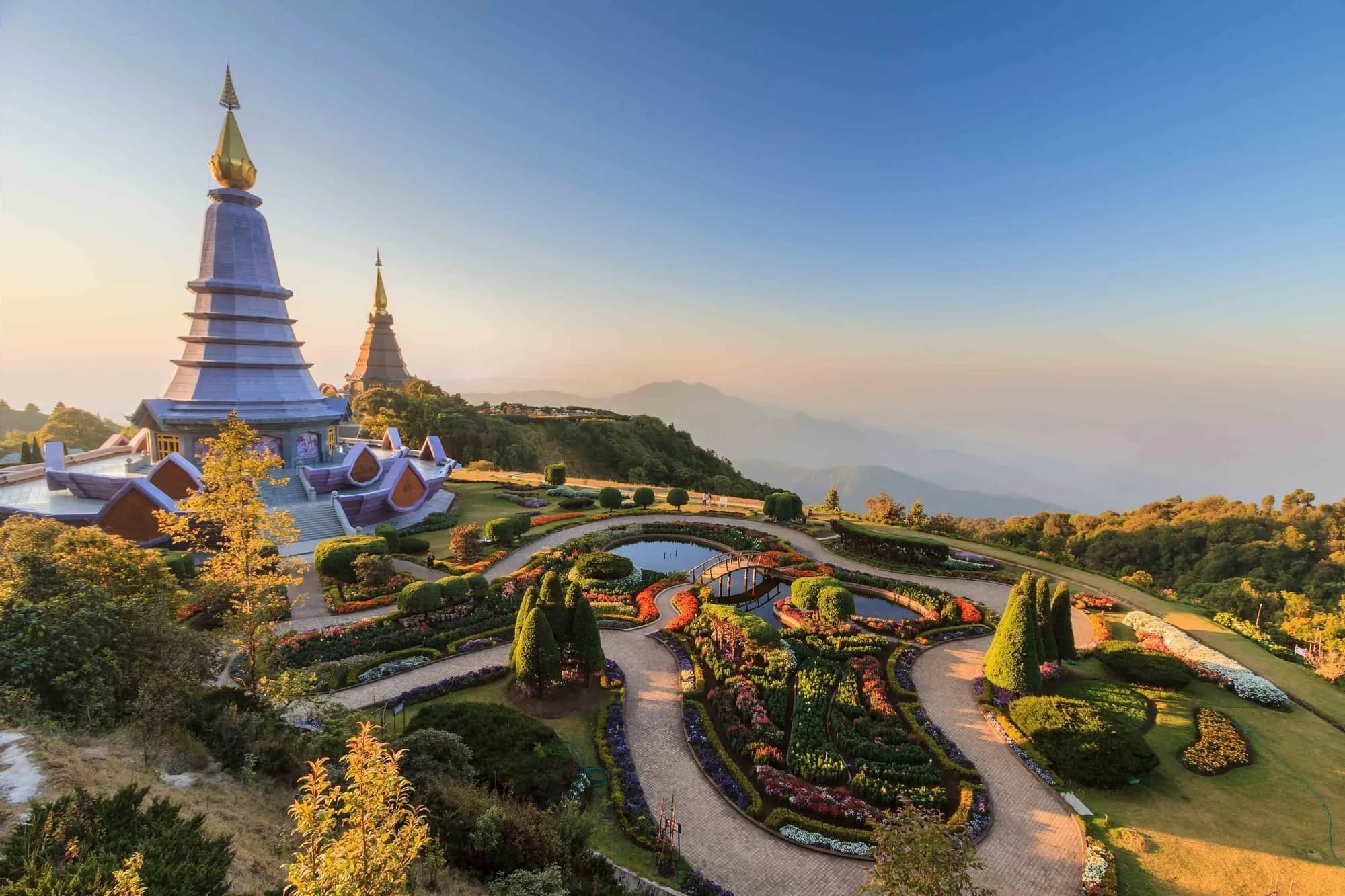 The twin royal pagodas on Doi Inthanon rise above landscaped flower gardens in early morning light.