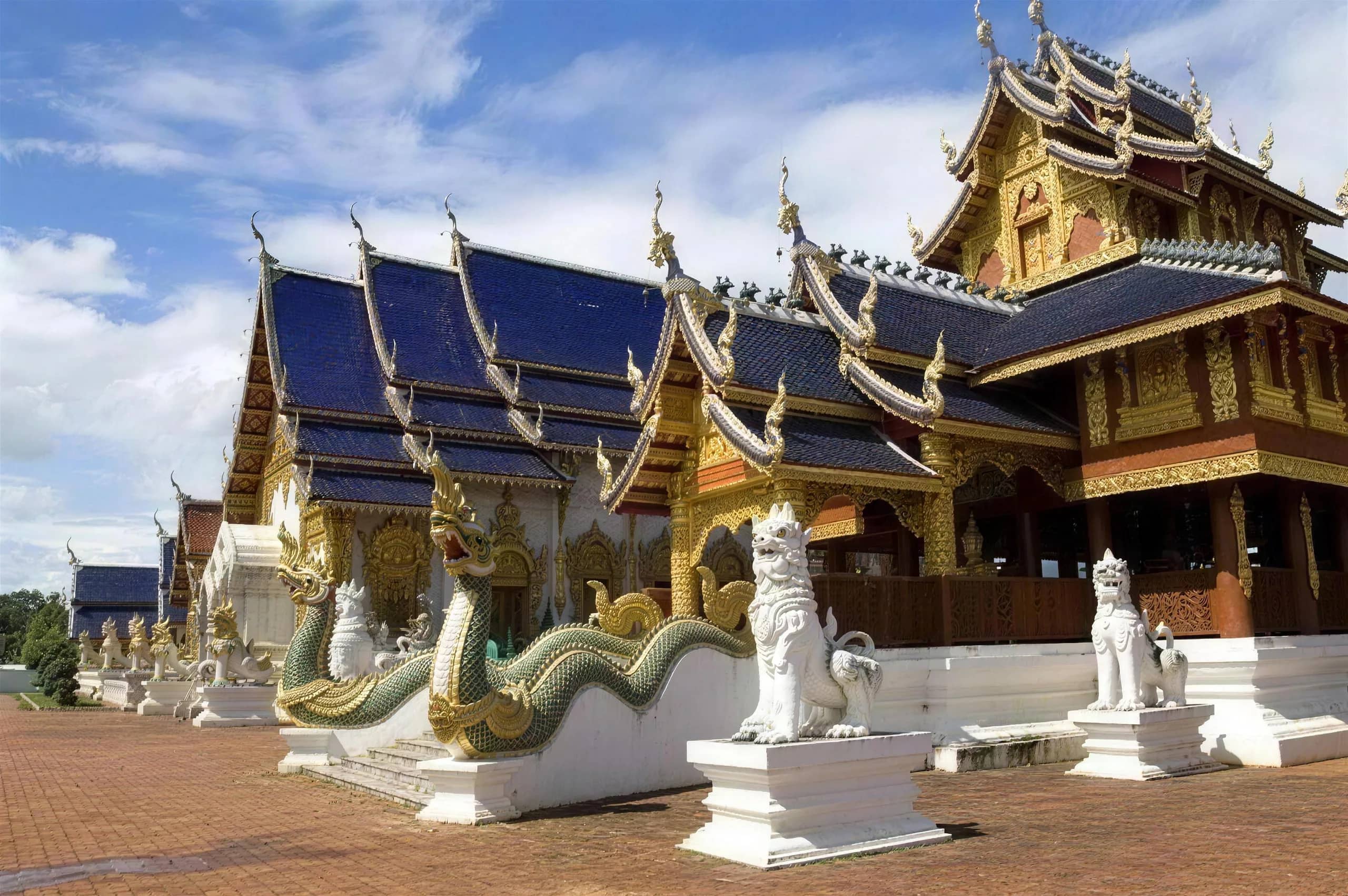Golden Lanna temple halls with naga serpent staircases and white lion statues at Wat Ban Den